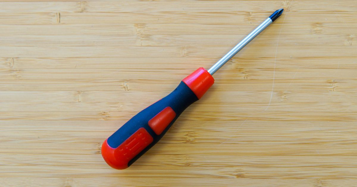 Red and black philips screwdriver sitting on a wooden table