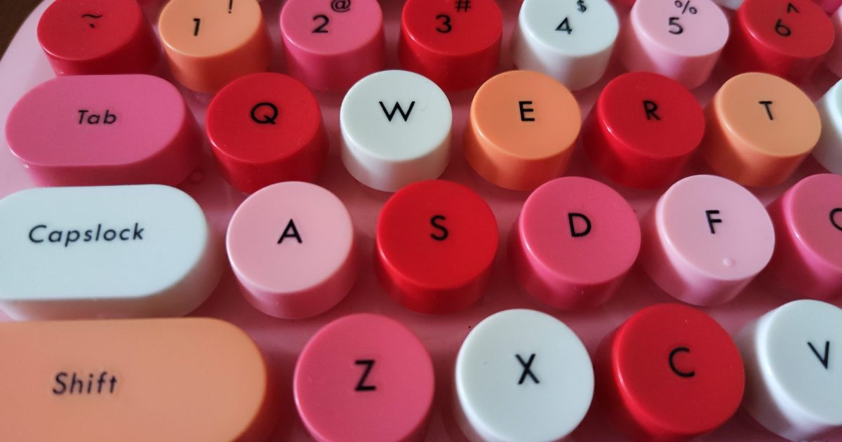 A close-up view of a colorful keyboard featuring round, brightly colored keycaps in shades of pink, red, and