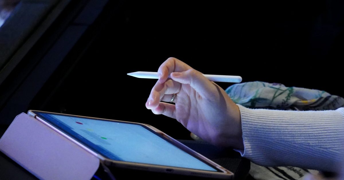 A person holding a stylus over a tablet screen, with the tablet resting on a case