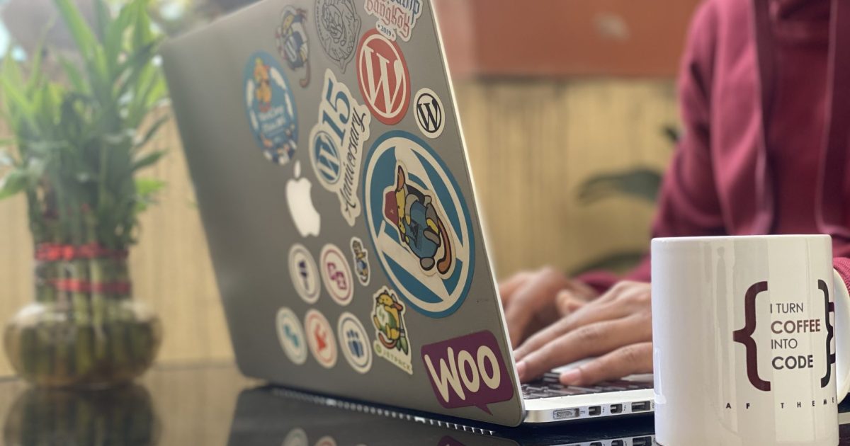 Man working on a Laptop with colorful stickers, representing achievements and community bonds