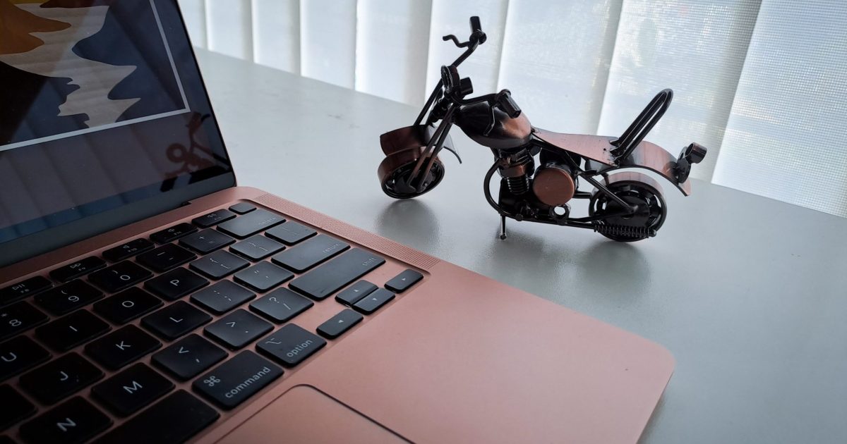 A laptop and a miniature of a motorbike in an office desk
