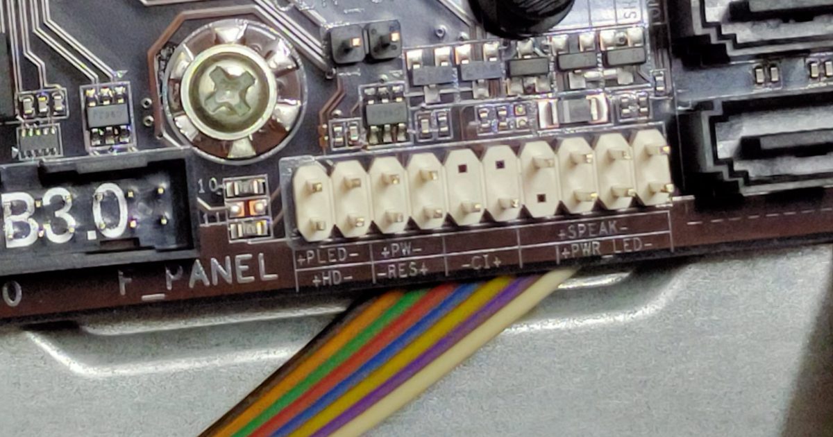 Close-up of a motherboard's front panel connectors with labels for power LED, speaker, reset switch and power