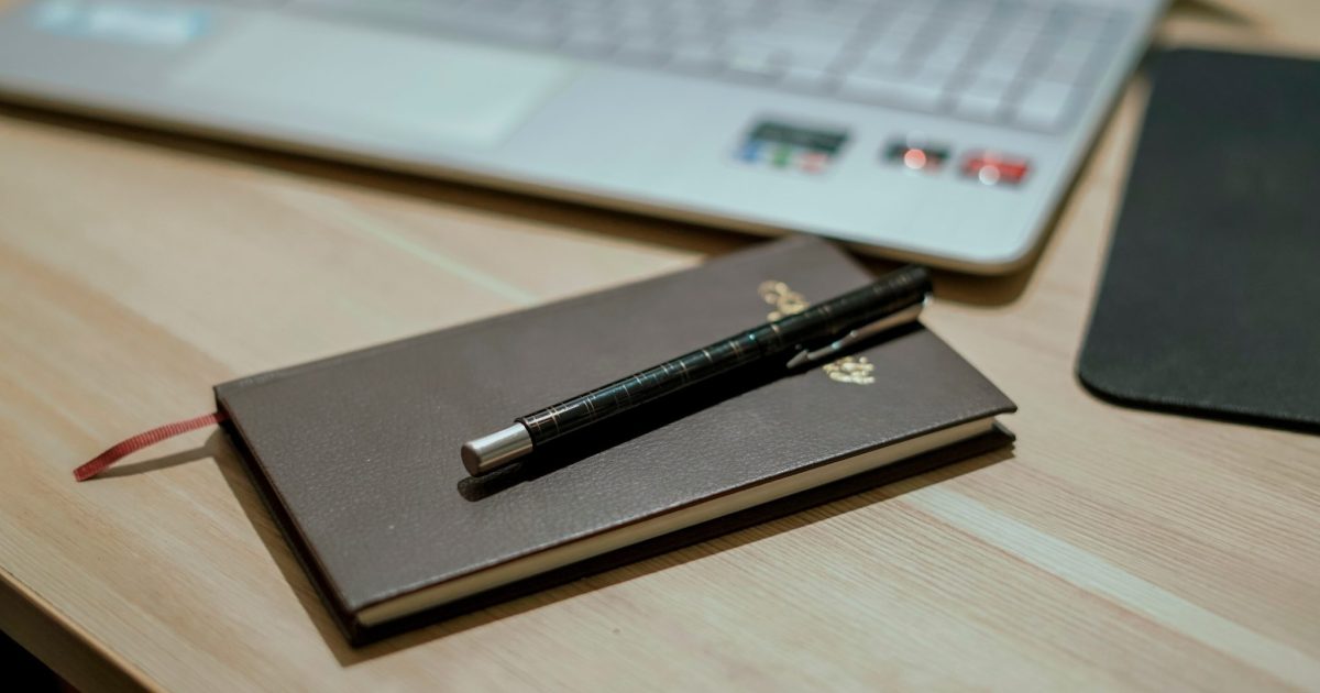 Black color book with a Premium ball pen placed on a wooden table