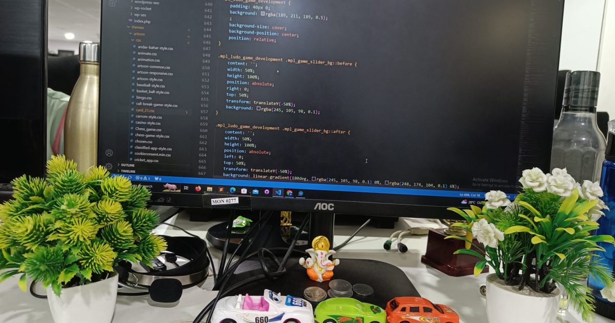 A view of the office desk with a monitor, water bottle, indoor plants, and cables