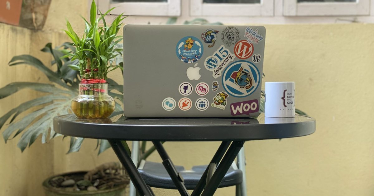 Laptop adorned with vibrant stickers illustrating a WordPress enthusiast's journey, on a table with a lucky